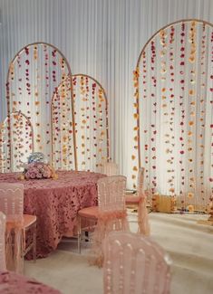 a banquet room set up with pink and gold decorations on the walls, white sheer drapes, and round table cloths