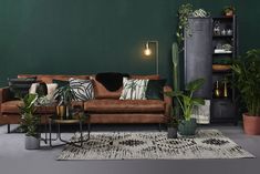 a living room with green walls and plants on the table in front of the couch