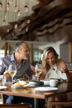 two people sitting at a table with wine glasses