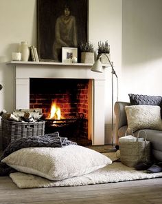 a living room with a fire place in the fireplace and blankets on the floor next to it