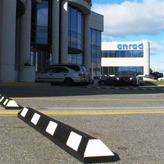 a parking lot with cars parked in front of an antrod building and two black and white striped barriers