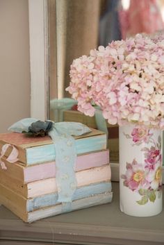 a vase filled with pink flowers next to a stack of books