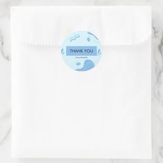 a white envelope with a blue thank you sticker on the front, and a paper bag in the back