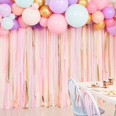 a party with balloons and streamers hanging from the ceiling, along with pastel colors