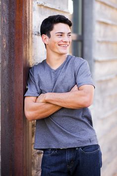 a young man leaning against a wall with his arms crossed