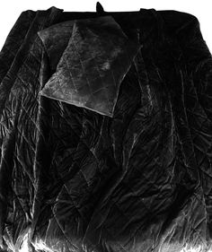 an image of a black quilted blanket on the ground with it's hood pulled back