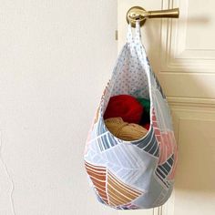 a bag hanging from a hook on a door with yarn in it and a ball of yarn inside