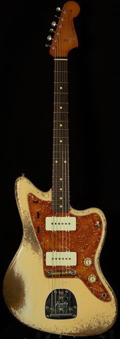 an old guitar is sitting on a black surface