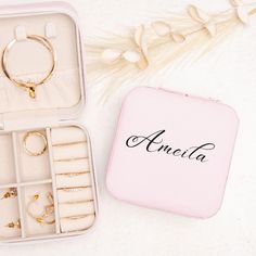 an open jewelry box with rings and bracelets in it on a white surface next to flowers