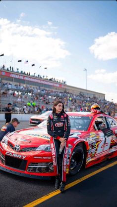 a woman sitting on the hood of a race car