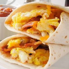 two breakfast burritos on a plate with salsa