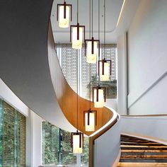 a spiral staircase with lights hanging from it's sides in a modern style home