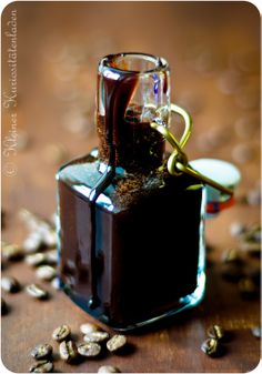 a glass bottle filled with liquid sitting on top of a wooden table next to seeds