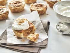 small pastries are sitting on napkins next to a bowl of cream and a spoon