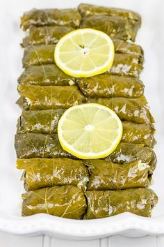 stuffed grape leaves with lemon wedges on a white platter