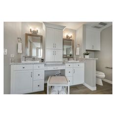 a white bathroom with two sinks, mirrors and a toilet in the corner next to it