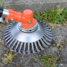 an orange and black blow dryer sitting on top of a cement floor next to grass