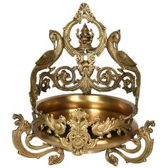 an ornate brass bowl with two birds on it's rim, sitting in front of a white background