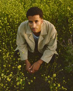 a man kneeling down in a field of flowers