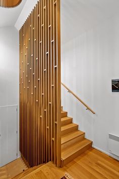 a wooden stair case next to a white wall