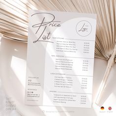 a price list sitting on top of a white plate next to a large palm leaf