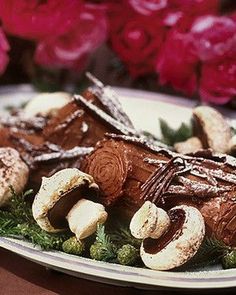 a white plate topped with chocolate covered desserts on top of a table next to pink flowers