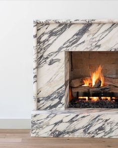 a white marble fireplace with logs burning in it