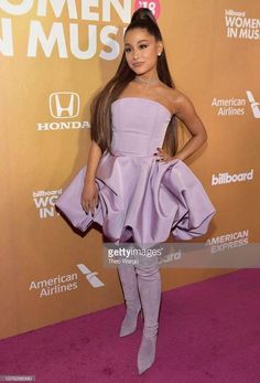 a woman in purple dress standing on pink carpet