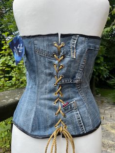 Handmade denim corset, reworked from authentic vintage Levi's jeans.  Complete with boning, black satin bias binding and a traditional corset lace up back. Size UK M/12-16 - all measurements are pictured, and the corset can be adjusted to fit with the lace up back. Super flattering and tailored , each panel is lined so extra sturdy thick fabric <3 Each of my items are one of one handmade designs and cannot be replicated exactly due to the nature of reworking vintage Levi's. If you like an item a Fitted Dark Wash Corset, Fitted Vintage Corset For Festivals, Vintage Fitted Corset For Festival, Festival Fitted Denim Bottoms, Fitted Denim Bottoms For Festival, Fitted High Waist Denim Blue Corset, Denim Corset Top Diy, Denim Blue High Waist Fitted Corset, Vintage Fitted Bottoms For Festival