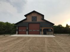 a large brown barn sitting in the middle of a dirt field next to some trees