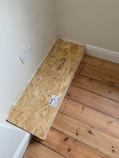 an unfinished room with hard wood flooring on the side and white wall in the background