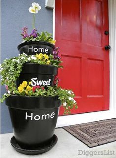 three flower pots are stacked on top of each other in front of a red door