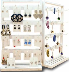 a white display case with earrings and earring hooks on the wall next to it