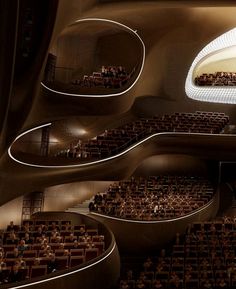 an auditorium filled with lots of people sitting in seats and looking up at the ceiling