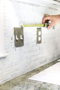 a person measuring the width of a white brick wall