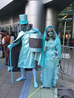 two people dressed in costumes standing next to each other on a sidewalk near a building