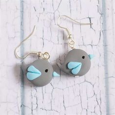 two gray birds with blue beaks are hanging from silver earwires on a white background