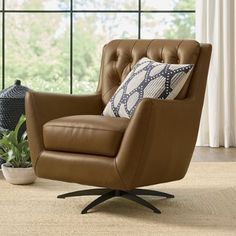 a brown leather chair sitting in front of a window next to a potted plant