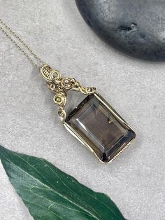 This gorgeous wire wrapped smokey quartz pendant features a stunning, giant smokey quartz emerald-cut facet wire wrapped in 14k gold filled wire. About the Pendant: - 100% handmade - Genuine, natural smokey quartz, 30mm x 20mm - Non-tarnish 14k gold filled wire - Safe for daily wear - Suitable for those with metal allergies or sensitivities - One-of-a-kind piece A 14k gold filled chain will be included with the pendant.  The piece will ship in a pendant box and will include care instructions in the package.  The piece will be professionally polished prior to shipping so that it arrives sparkling and ready to wear. Return Policies: Our work is guaranteed!   - We offer repair services as well as intermittent polishing services at the buyer's request.  If you ever have an issue with your piec Elegant Smoky Quartz Gemstone Necklace, Wire Wrapped Crystal Pendant, Smoky Quartz Necklace, Crystal Statement Necklace, Wire Wrapping Crystals, Jewelry Crystal, Necklace Unique, Necklace Gemstone, Unique Handmade Jewelry