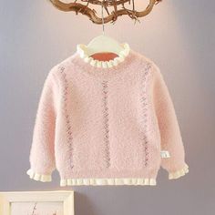 a pink sweater hanging on a clothes rack next to a framed photograph and tree branch