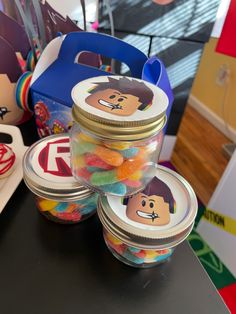 three jars filled with different colored candies on top of a black table next to other items