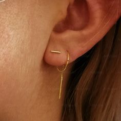 a close up of a person's ear with a gold chain attached to it