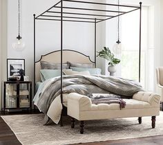 a bedroom with a four poster bed and white walls