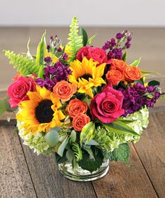 a vase filled with colorful flowers on top of a wooden table