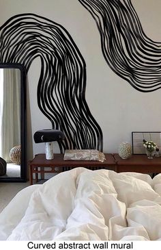 a bed sitting under a large mirror next to a black and white painting on the wall