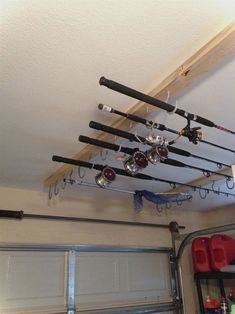 there are many fishing rods hanging from the ceiling in front of garage doors and overhead lights