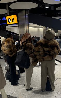 people standing in line at an airport waiting for their luggage