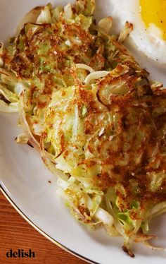 an egg is on top of some cabbage and hashbrowns are on the plate