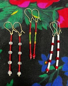 three pairs of beaded earrings sitting on top of a flowered cloth covered table