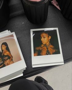 two polaroid pictures are sitting on a table next to a trash can and a person's feet